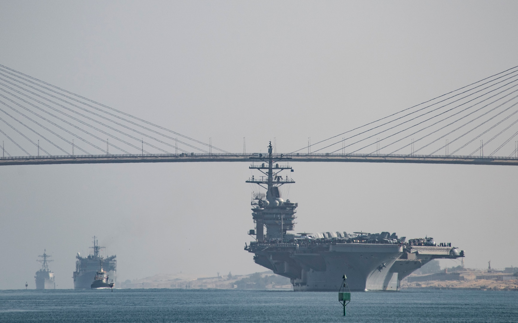 The aircraft carrier USS Dwight D. Eisenhower (CVN 69), followed by the fast combat support ship USNS Arctic (T-AOE 8) and the guided-missile destroyer USS Nitze (DDG 94), pass under the Freedom Bridge while transiting the Suez Canal. The Eisenhower Carrier Strike Group is deployed in support of maritime security operations and theater security cooperation efforts in the U.S. 5th Fleet area of operations. 