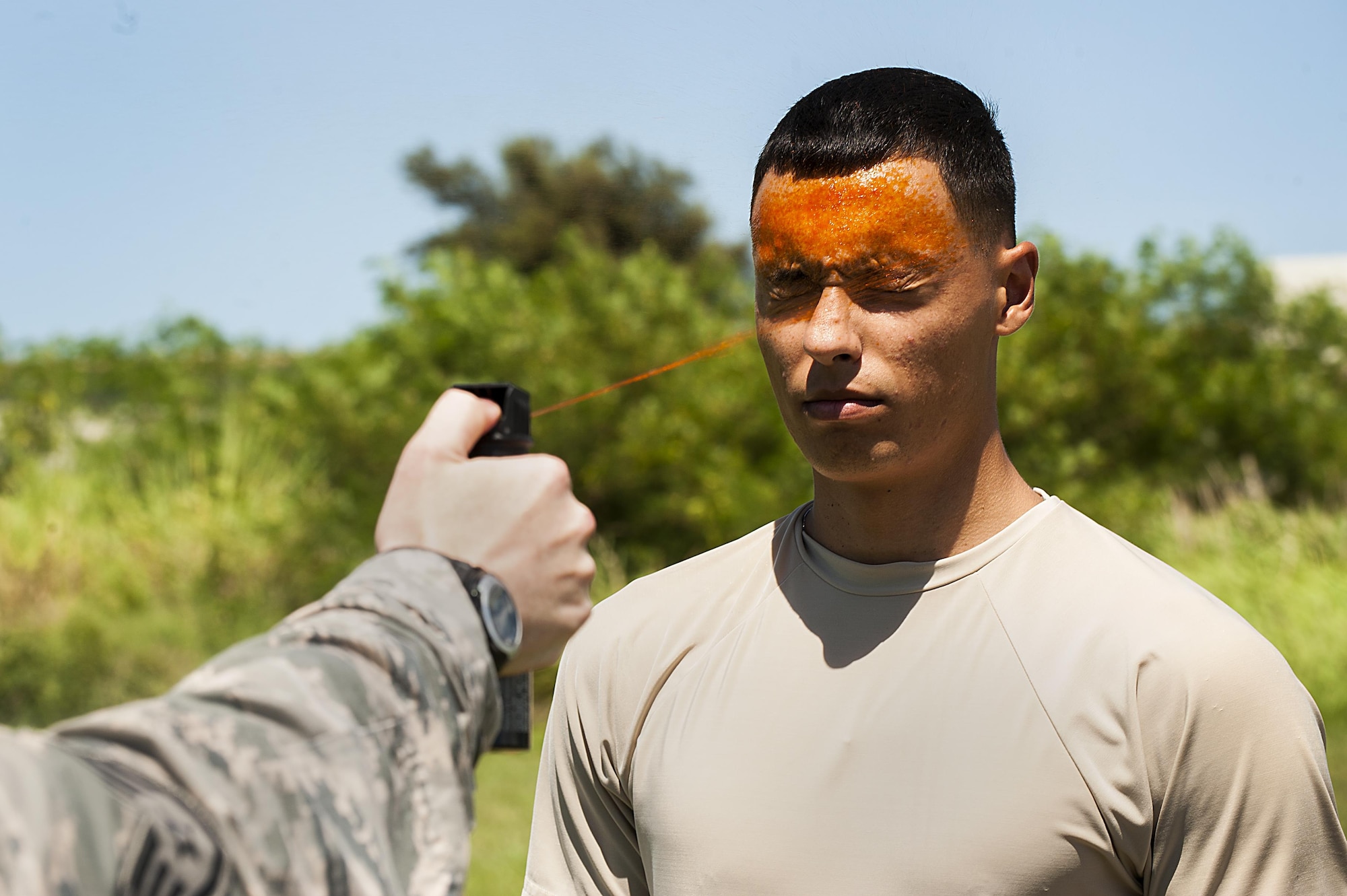 U.S. Air Force Airman 1st Class Dustin Sullivan, 18th Security Forces Squadron response force member, gets sprayed in the eyes with OC spray during training July 13, 2016 at Kadena Air Base, Japan. In order to be certified to use OC spray, SFS members must be sprayed and complete an obstacle course involves M-9 pistol reloading, subduing someone in a red-man suit and carrying water jugs around cones. (U.S. Air Force photo by Airman 1st Class Corey M. Pettis)