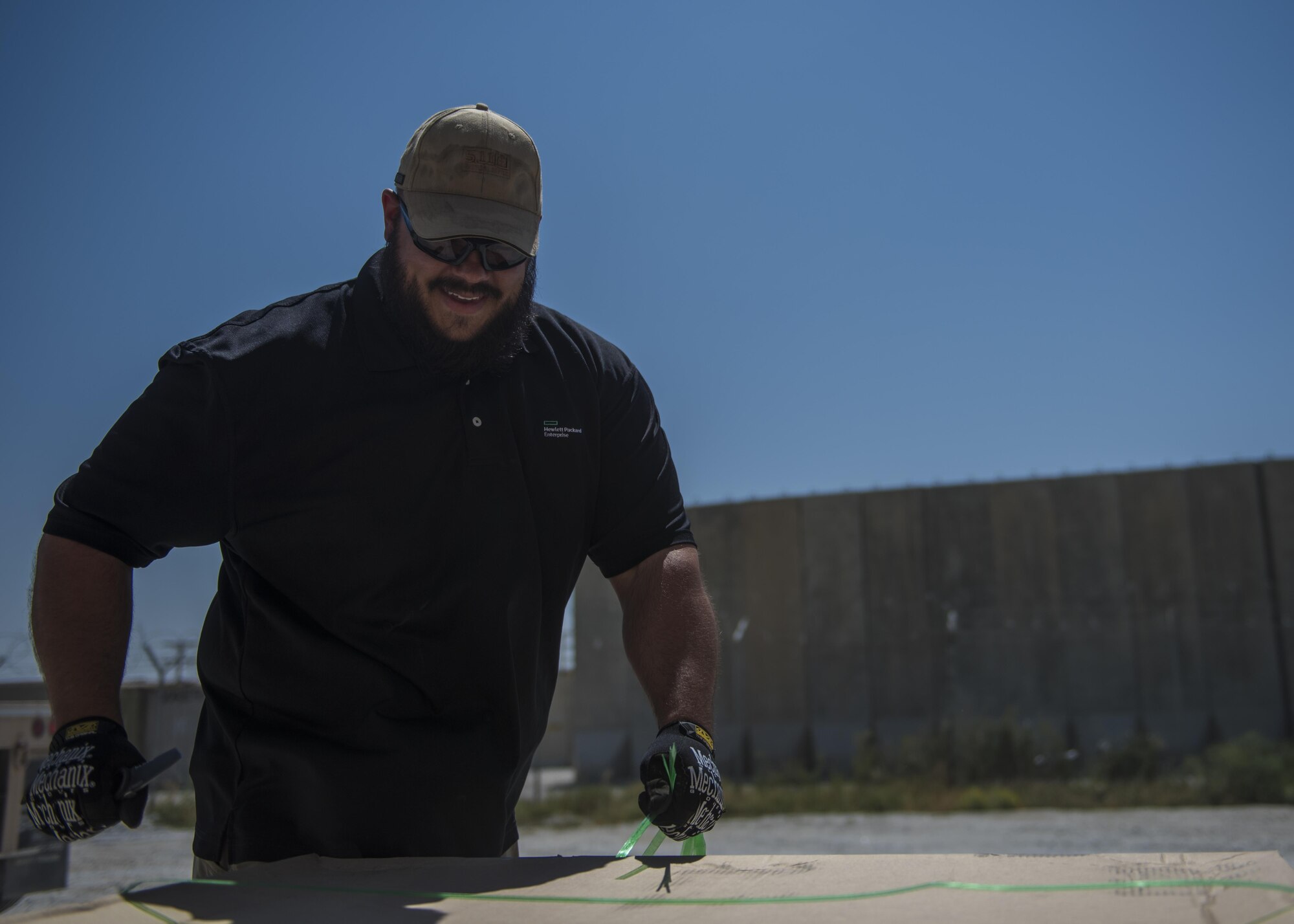 Mr. Shaun Cole, 455th Expeditionary Communications Squadron knowledge management, cuts the binding on a mail tri-wall, July 13, 2016, Bagram Airfield, Afghanistan. Mail tri-walls contain packages and letters that have been shipped from the United States or abroad. (U.S. Air Force photo by Senior Airman Justyn M. Freeman)