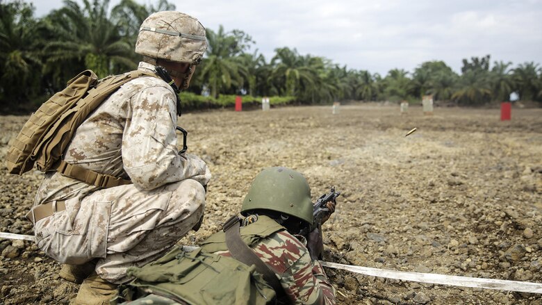 Lance Cpl. Christopher Parsons, a rifleman with Special Purpose Marine Air-Ground Task Force Crisis Response-Africa, watches a Cameroonian soldier with Forces Fusiliers Marins et Palmeurs de Combat shoot their weapon on the range in Limbé, Cameroon, July 1, 2016.  Marines share tactics, techniques and skills with the FORFUMAPCO soldiers to combat the illicit trafficking in Cameroon. 