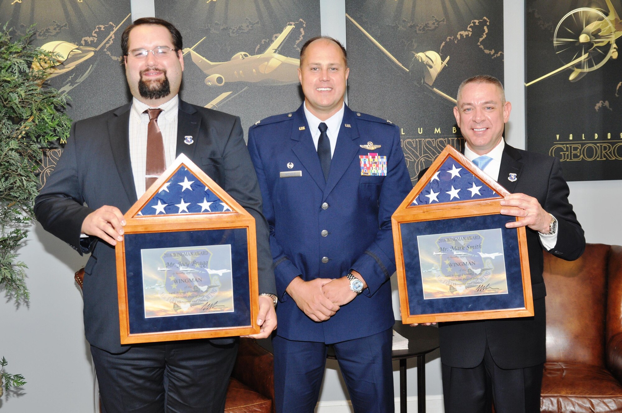 Col. John Nichols, 14th Flying Training Wing Commander, center, stands on July 12 with Joey Bragg, left, and Mark Smith, right, the two newest Columbus Wingmen at the Columbus Club on Columbus Air Force Base, Mississippi. The Columbus Wingman Award is an honorary designation that recognizes outstanding members of the community who have made exceptional contributions to the base. (U.S. Air Force photo/Sonic Johnson)