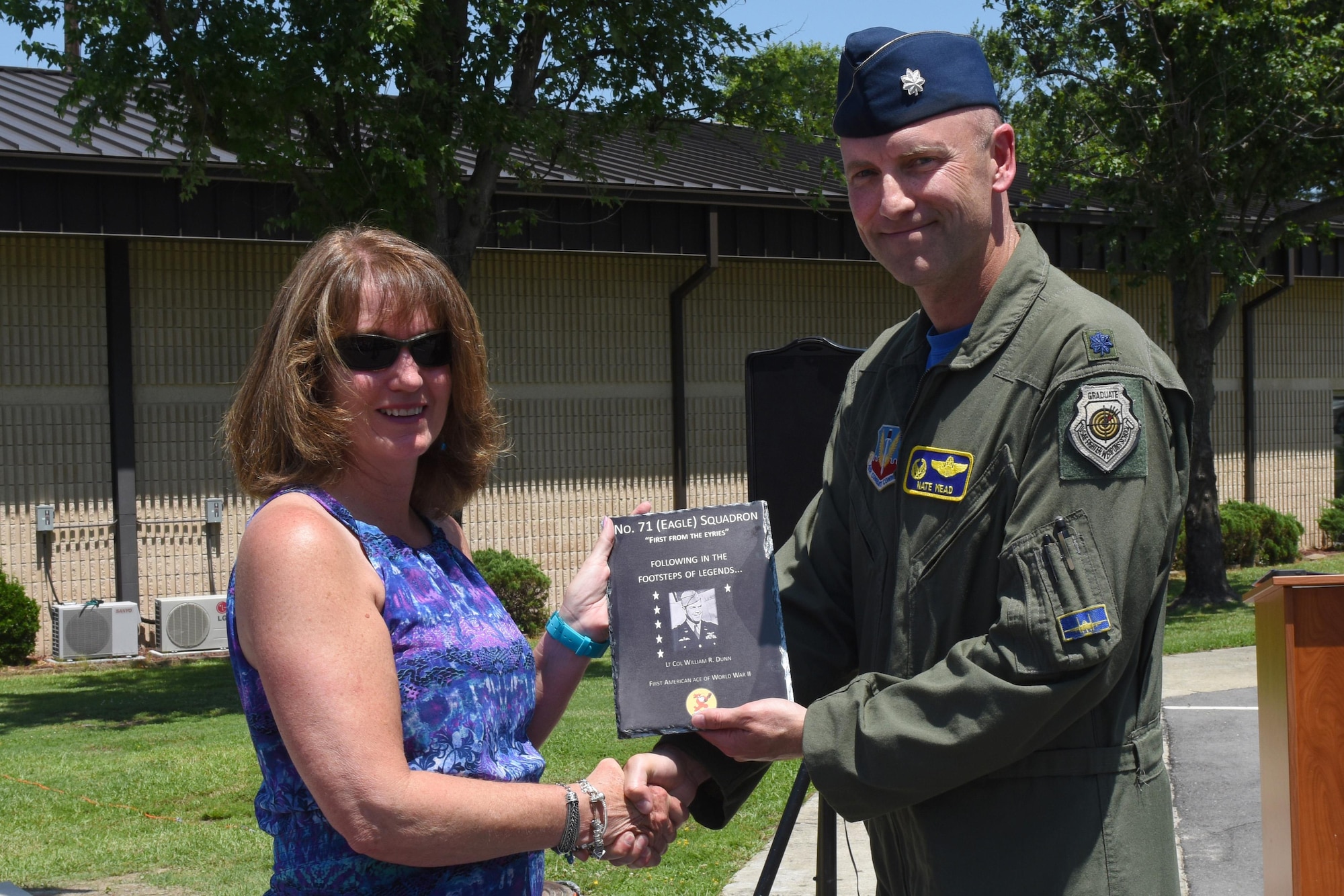Lt. Col. Nathan Mead, 334th Fighter Squadron commander, presents a plaque to Felicia Hutto, granddaughter of William Dunn, British Royal Air Force Squadron 71 member and first American ace of World War II, during the unveiling of a memorial dedicated to the RAF members, July 8, 2016, at Seymour Johnson Air Force Base, North Carolina. Family members of the No. 71 (Eagle) Squadron service members came from all over the country to attend the ceremony. (U.S. Air Force photo by Airman 1st Class Ashley Williamson)