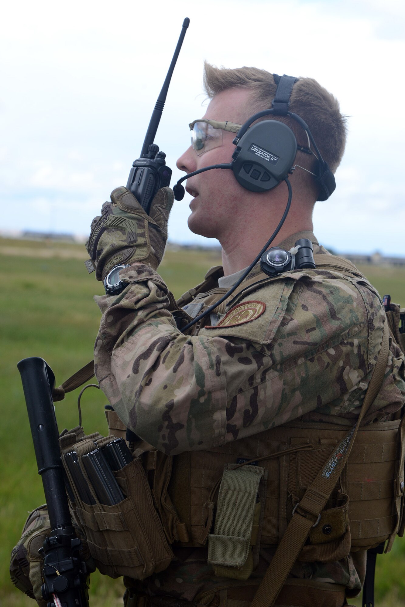Senior Airman William Lamb, 741st Missile Security Forces Squadron Tactical Response Force member, talks into a land mobile radio to communicate with an aircrew in an UH-1N Iriquois at a mock launch facility July 6, 2016, at Malmstrom Air Force Base, Mont. TRF maintains communication with the 40th Helicopter Squadron aircrew to update the status on the ground and to coordinate pick-up or reposition. (U.S. Air Force photo/Staff Sgt. Delia Marchick)