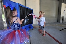 A child waves an American Flag in front of a fan during Operation Homecoming at Hurlburt Field, Fla., July 7, 2016. This event welcomed several Airmen home after a deployment overseas in support of Operation Inherent Resolve. (U.S. Air Force photo by Airman Dennis Spain)