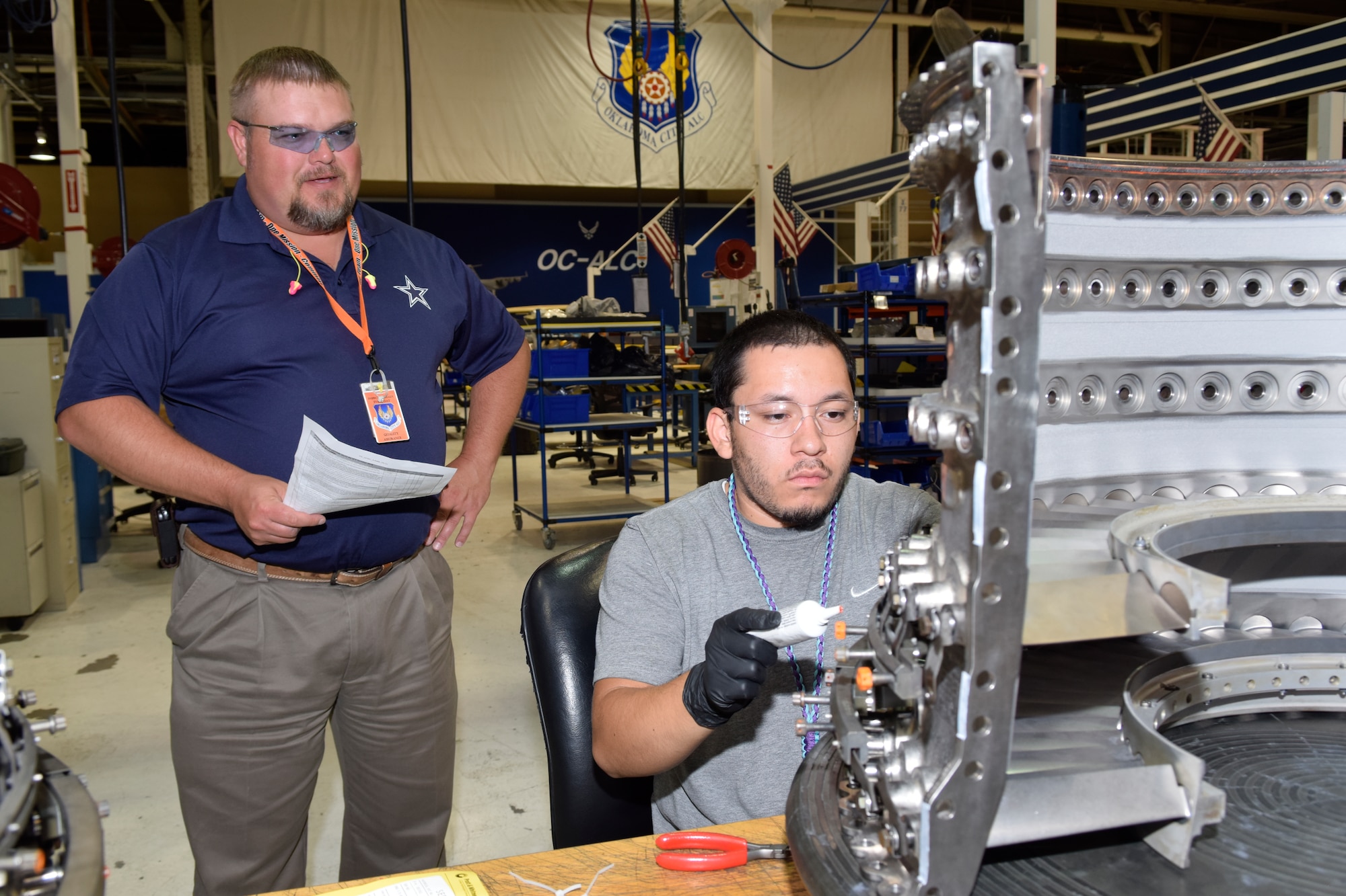 Preston Argo, Oklahoma City Air Logistics Complex quality assurance inspector, performs an evaluation of Samuel Cervantes, jet engine mechanic, while he installs compressor vanes on a split-case of a F117 engine used on C-17A Globemaster III aircraft June 13, 2016, Tinker Air Force Base, Okla. Argo, the QA inspector, works closely with Cervantes to ensure critical assembly steps are completed in the proper order and done to specifications in a partnership versus adversarial role. (U.S. Air Force photo/Greg L. Davis)