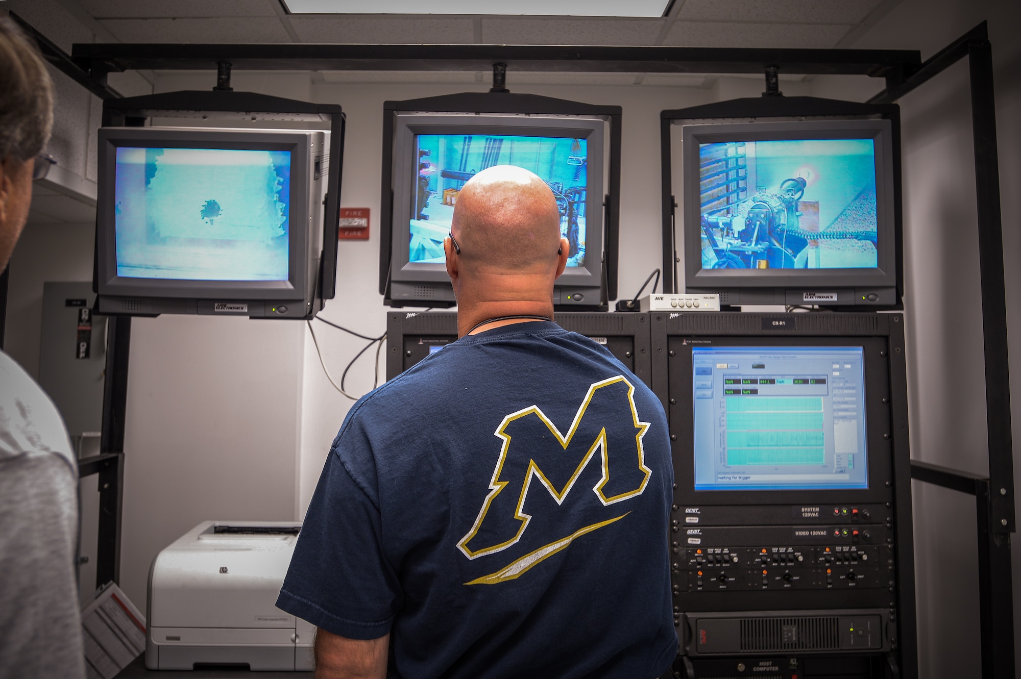 John Baker, a 531st Commodities Maintenance Squadron aircraft ordnance system mechanic, remotely fires a 20 mm gun during a qualification test at Hill Air Force Base, Utah, May 25, 2016. Technicians and gun shop visitors can see what happens inside the test range on the bank of monitors pictured. (U.S. Air Force photo by R. Nial Bradshaw)