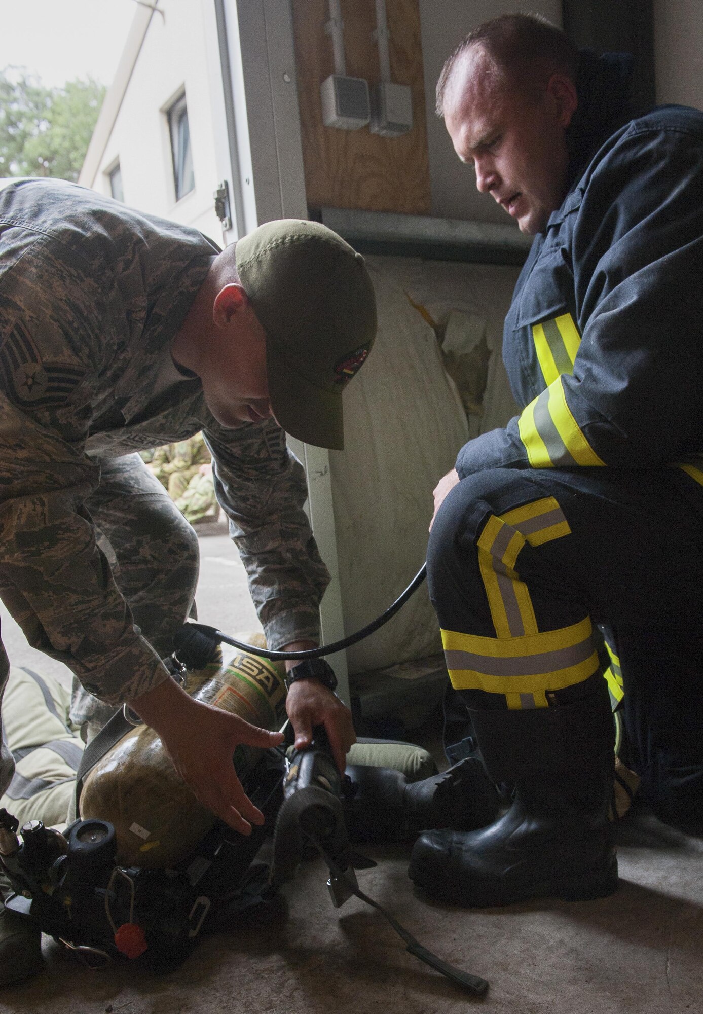 Lithuanian air force Major Tomas Zukauskas, firefighter, takes his gear off with the help of U.S. Air Force Staff Sgt. Anthony Montano, 435th Construction and Training Squadron contingency firefighting operations instructor, after participating in a training exercise July 11, 2016, at Ramstein Air Base, Germany. The training included close-quarters maneuverability that involves multi-level platforming and retrieving “training dummies” as they simulate saving people out of a trapped situation.