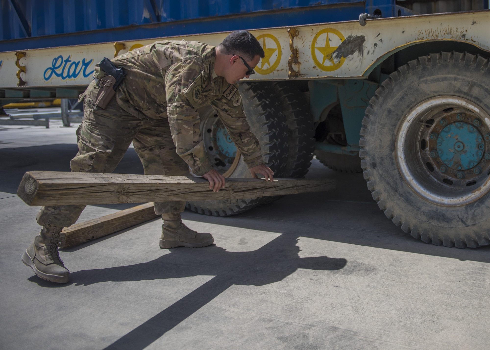 Senior Airman Brandon Misita, 455th Expeditionary Logistics Readiness Squadron Central Command material recovery element, throws a beam in front of a truck tire during a high mobility multipurpose wheeled vehicle delivery, July 14, 2016, Bagram Airfield, Afghanistan. Misita places beams in front of the tires so the truck stays stable as the CMRE team unloads the cargo. (U.S. Air Force photo by Senior Airman Justyn M. Freeman)