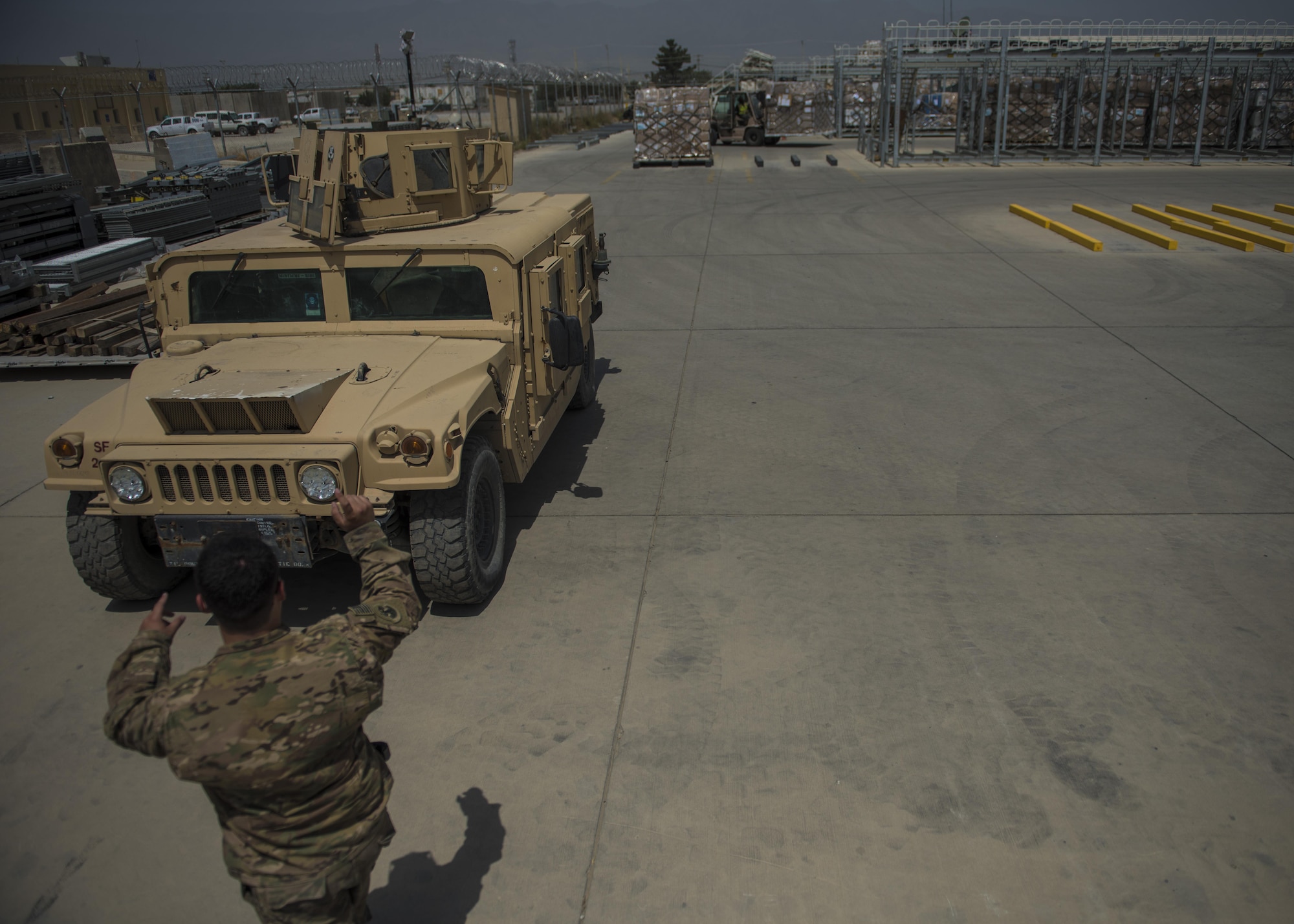 Senior Airman Brandon Misita, 455th Expeditionary Logistics Readiness Squadron Central Command material recovery element, guides a high mobility multipurpose wheeled vehicle July 14, 2016, Bagram Airfield, Afghanistan. Members of the 455th ELRS CMRE team traveled to Hamid Karzai International Airport, Kabul to ship two retrograde HMMWVs back to Bagram for vehicle maintenance inspection. (U.S. Air Force photo by Senior Airman Justyn M. Freeman)