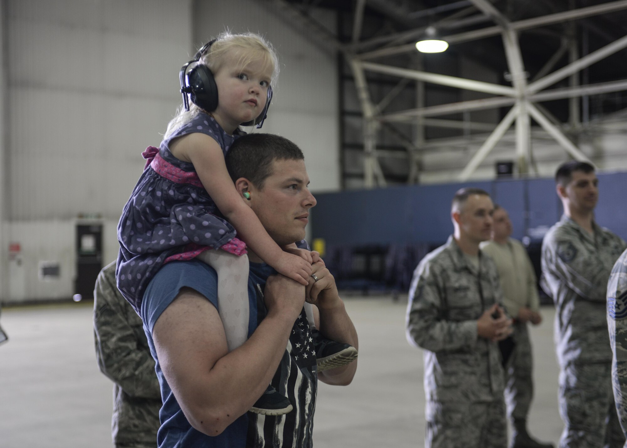 Staff Sgt. Mark Doke, 48th Maintenance Group weapons load team chief, and his daughter, Amelia, watch a 48th MXG quarterly load crew competition at Royal Air Force Lakenheath, England, July 11. Family members cheered for the Airmen assigned to the 748th and 48th Aircraft Maintenance Squadrons, as they competed for the title of best load crew team of the quarter. (U.S. Air Force photo/Senior Airman Nigel Sandridge)