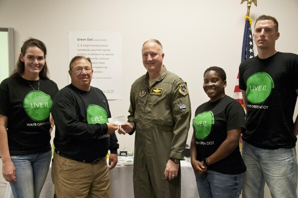 U.S. Air Force Col. Gregory Eckfeld, 442nd Fighter Wing vice commander, center, presents a check to Robin Smith, director of the 509th Bomb Wing Airman and Family Readiness Center, to support the Green Dot program at Whiteman Air Force Base, Mo., July 14, 2016. Eckfeld is representing the 442nd FW Human Resources Development Council that is donating money in support of Green Dot.  (U.S. Air Force photo by Senior Airman Missy Sterling)