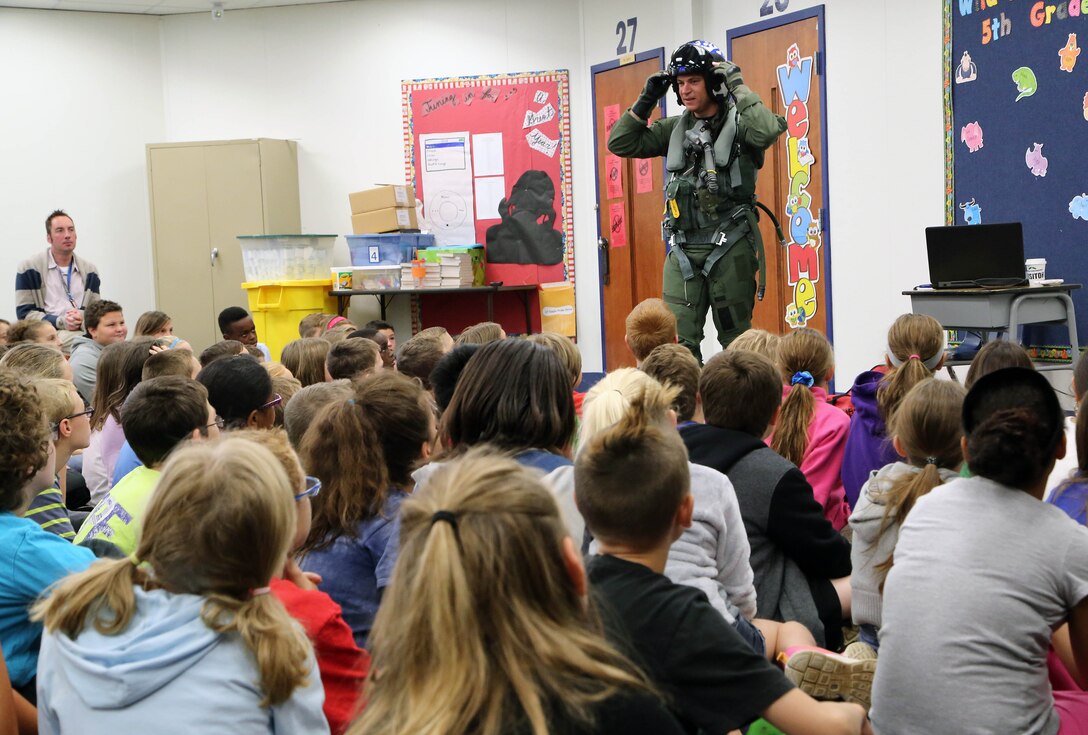 Navy Lt. Cmdr. Doug Crane, Defense Contract Management Agency Boeing St. Louis government flight representative, provides local students with an overview of his flight gear focused on the science and safety aspects to include the air-inflatable pressure pants and anti-gravity suits during a recent science, technology, engineering and mathematics outreach program event.