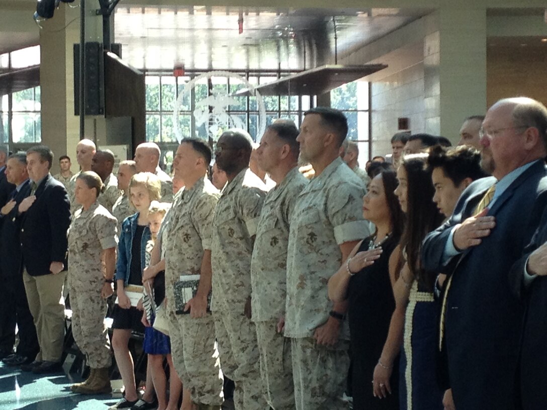 Attendees and participants stand at attention during the playing of the National Anthem at the change of command ceremony for MCIOC at the National Museum of the Marine Corps on June 30, 2016.