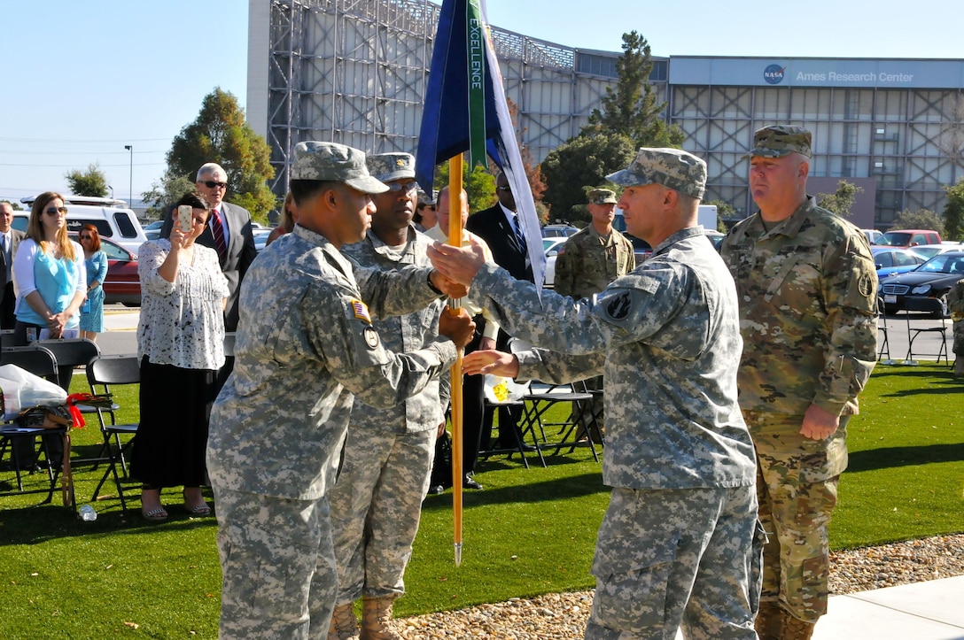 Lt. Col. Michael Stewart (second right), company commander, Headquarters and Headquarters Company, 63rd Regional Support Command, passes the company guidon to Sgt. 1st Class. Francisco Matos, acting first sergeant, HHC, 63rd RSC, during the traditional passing of the unit colors at a change of command ceremony, July 13, Armed Forces Reserve Center, Mountain View, Calif. Stewart assumed command from outgoing commander Maj. Derrick Carter (second left). Overseeing the ceremony is Maj. Gen. Nick Tooliatos (right), commanding general, 63rd RSC.