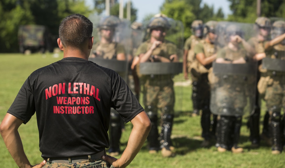 A non-lethal weapons instructor with 2nd Law Enforcement Battalion, watches Marines with 3rd Battalion, 2nd Marine Regiment practice riot control formations and tactics during a non-lethal weapons course at Marine Corps Base Camp Lejeune, North Carolina, July 15, 2016. Throughout the course they learned about various take-down techniques utilizing a police baton, riot control formations and tactics as well as the function and result of using a taser.