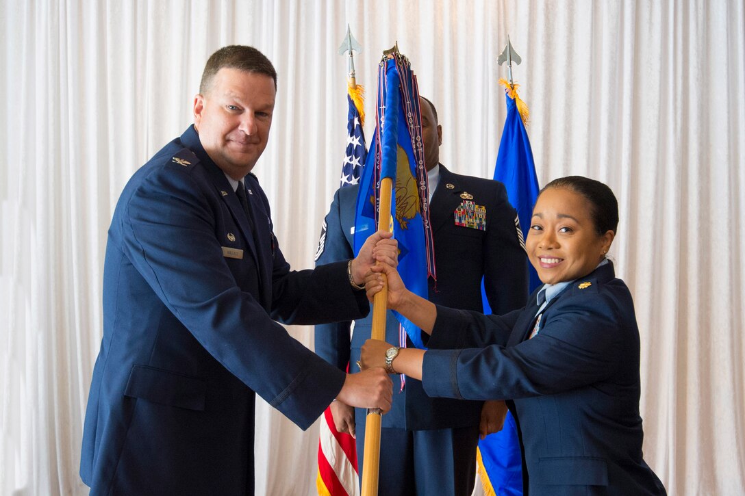 Col. Matthew Wallace, 45th Mission Support Group commander, presents Maj. Chong Gregory, 45th Force Support Squadron commander, with a guidon during a change of command ceremony July 15, 2016, at Patrick Air Force Base, Fla. Changes of command are a military tradition representing the transfer of responsibilities from the presiding official to the upcoming official. (U.S. Air Force photo/James Rainier/Released)