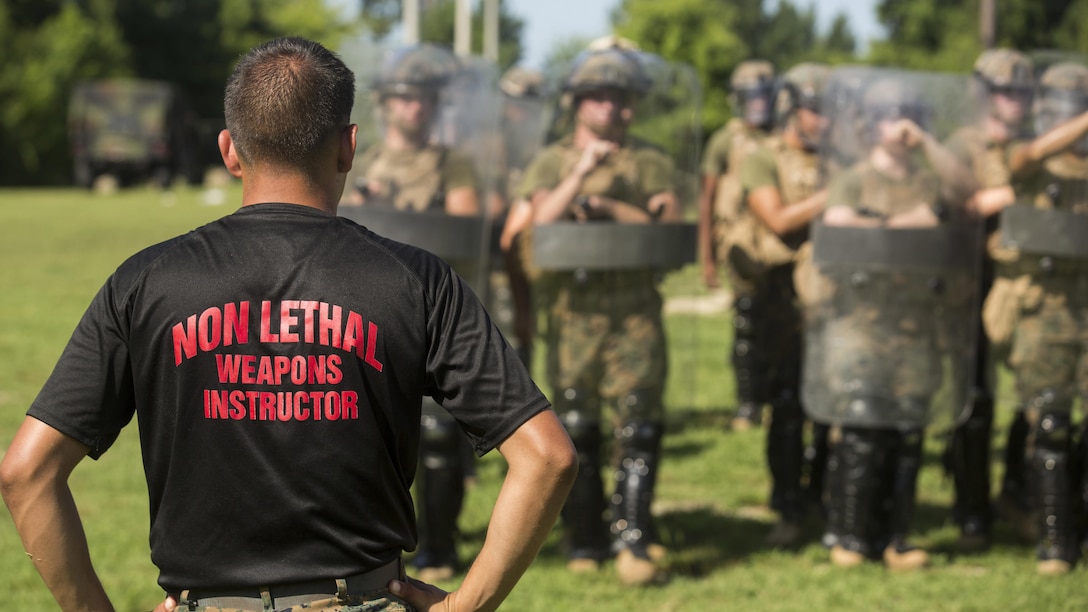 A non-lethal weapons instructor with 2nd Law Enforcement Battalion, watches Marines with 3rd Battalion, 2nd Marine Regiment practice riot control formations and tactics during a non-lethal weapons course at Marine Corps Base Camp Lejeune, North Carolina, July 15, 2016. Throughout the course they learned about various take-down techniques utilizing a police baton, riot control formations and tactics as well as the function and result of using a taser. 