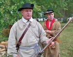 Dressed in typical attire of back-country riflemen, Revolutionary War living historians in Virginia prepare for a reenactment. The round hats and hunting shirts are the same as those described in the accounts of the first riflemen within companies such as the Berkeley County Rifles who made the “Beeline to Boston.” 