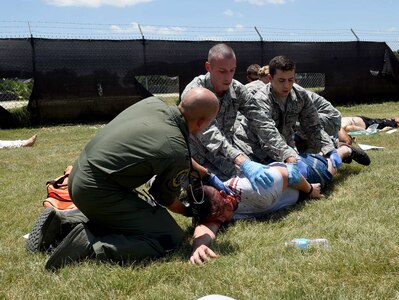 Airmen from the 59th Medical Wing roll a simulated patient on its back to better assess its injuries during a disaster response exercise July 13, 2016 at Camp Bramble on Joint Base San Antonio-Lackland, Texas. More than 50 disaster response team members participated in the exercise, which simulated an aircraft crash designed to test the team’s ability to respond and treat patients in the event of a real-world incident. (U.S. Air Force photo/Staff Sgt. Jerilyn Quintanilla) 