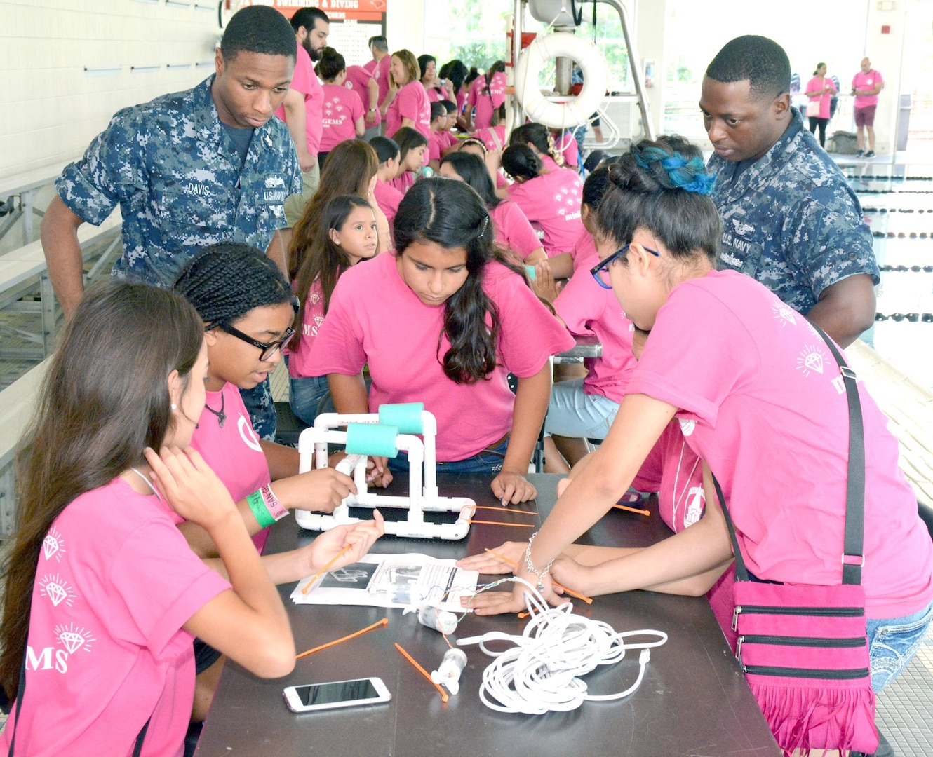 Navy recruiters, Machinist’s Mate 2nd Class Deron Davis of Navy Recruiting Station (NRS) Hollywood Park and Aviation Boatswain’s Mate 2nd Class Benjamin Brown of NRS De Zavala observe middle school girls assemble an underwater remotely operated vehicle (ROV) during a SeaPerch Competition held at the Ann Barshop Natatorium on the campus of the University of the Incarnate Word as a part of the miniGEMS (Girls in Engineering, Math and Sciences) program.  SeaPerch is an innovative underwater robotics program that equips teachers and students with the resources they need to build an underwater ROV in an in-school or out-of-school setting.  Davis, a native of Nacogdoches, Texas, is a graduate of Chireno High School in Chireno, Texas, and Brown, a native of Albany, Ga., graduated from Westover High School.  (U.S. Navy Photo by Burrell Parmer, Navy Recruiting District San Antonio Public Affairs/Released)