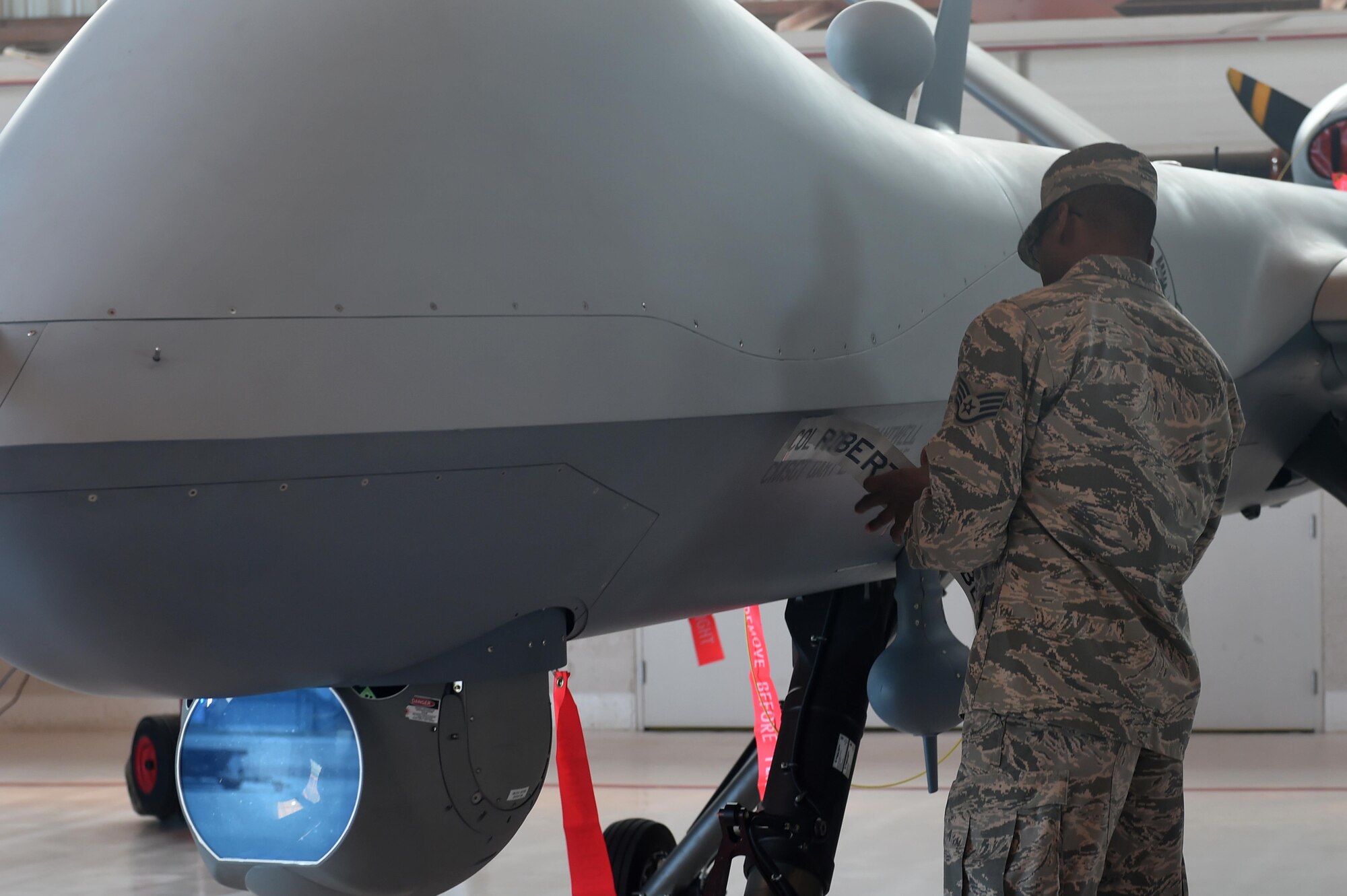 Staff Sgt. Malcolm, a member of the 49th Aircraft Maintenance Squadron, removes tape to reveal the name of Col. Houston Cantwell, the 49th Wing commander, during a change of command ceremony at Holloman Air Force Base, N.M., on July 15. As the incoming commander, Cantwell has already made plans to strengthen Holloman’s role in advancing the world’s best remotely piloted aircraft enterprise. (Last names are being withheld due to operational requirements. U.S. Air Force photo by Staff Sgt. Eboni Prince)