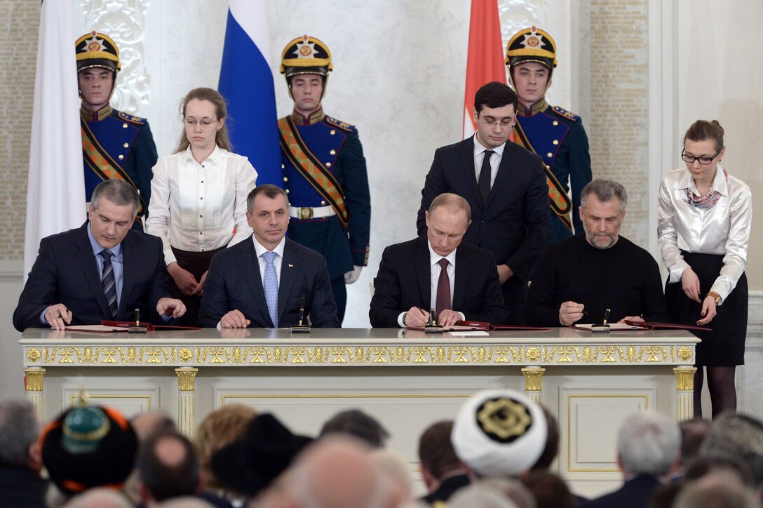Leaders from Russia and Crimea sign the treaty of accession, completing the annexation of Crimea on March 18, 2014.