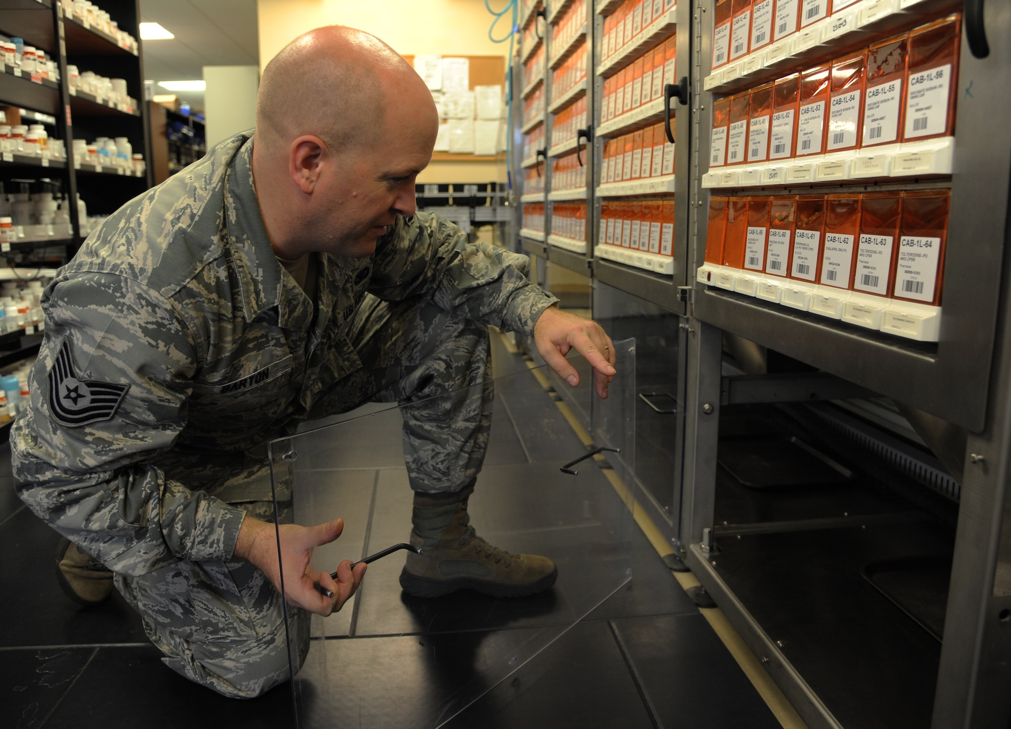 Tech. Sgt. Michael Barton, section chief of PharmaCARE drive-thru operations assigned to the 6th Medical Group, inspects the automatic prescription dispensary system inside the PharmaCARE center at MacDill Air Force Base, Fla., July 12, 2016. The automatic system assists the drive-thru pharmacy technicians to fill approximately 1,200 to 2,000 prescriptions daily. (U.S. Air Force photo by Airman Adam R. Shanks)