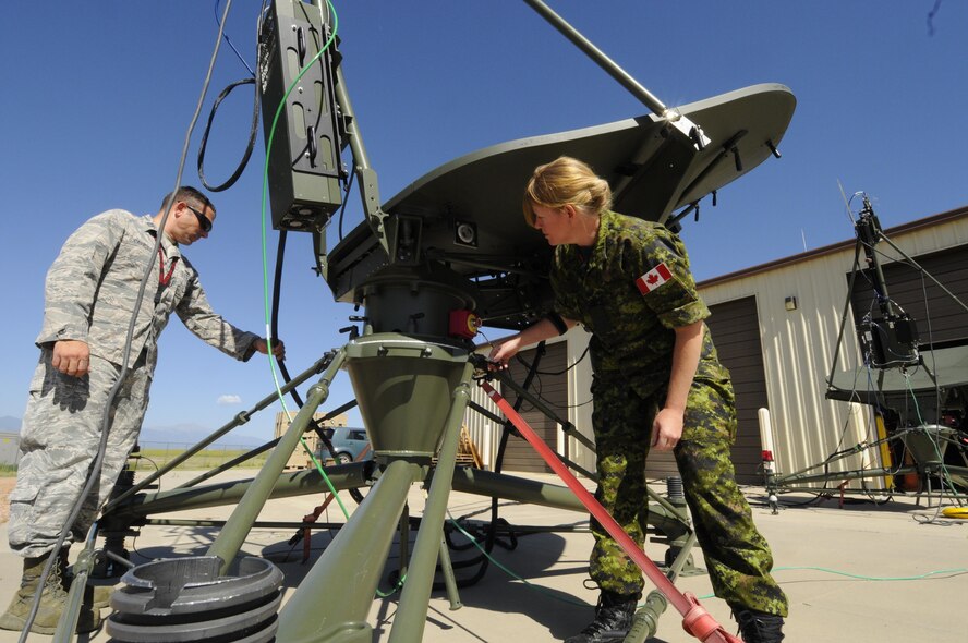 Capt. Dustyn Carroll, 527th Space Aggressors Squadron Aggressor Training flight commander, and Maj. Sheri Lattemore, assistant director of operations and Canadian liason officer to the 527th, set up a ground multi-band terminal antenna outside the 527 SAS’s facility at Schriever Air Force Base, Colorado, Tuesday, July 11, 2016. The 527 SAS and 26th Space Aggressors Squadrons are the only Space Aggressors in the Department of Defense. (U.S. Air Force photo/2nd Lt. Darren Domingo)