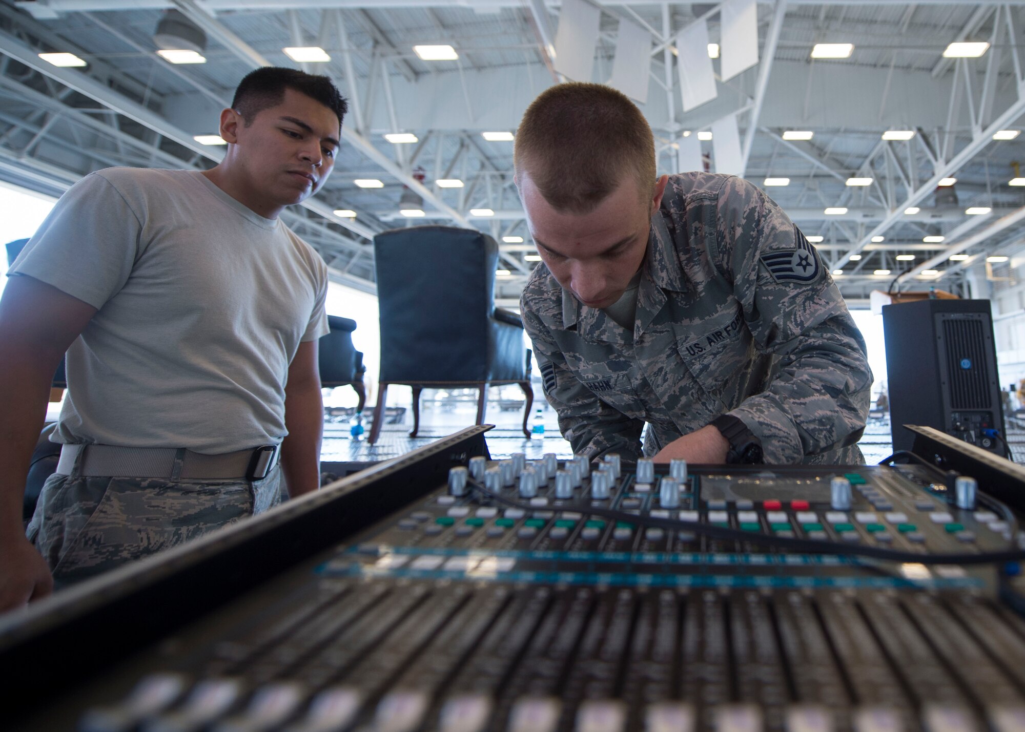 Senior Airman Roy Lizardo, left, and Staff Sgt. Andrew Muhlhahn, radio frequency systems journeymen with the 1st Special Operations Communications Squadron, sets up audio equipment for a change of command ceremony at the Freedom Hangar on Hurlburt Field, Fla., July 15, 2016. 1st SOCS Airmen provide audio support for different ceremonies and events on base. (U.S. Air Force photo by Senior Airman Krystal M. Garrett)