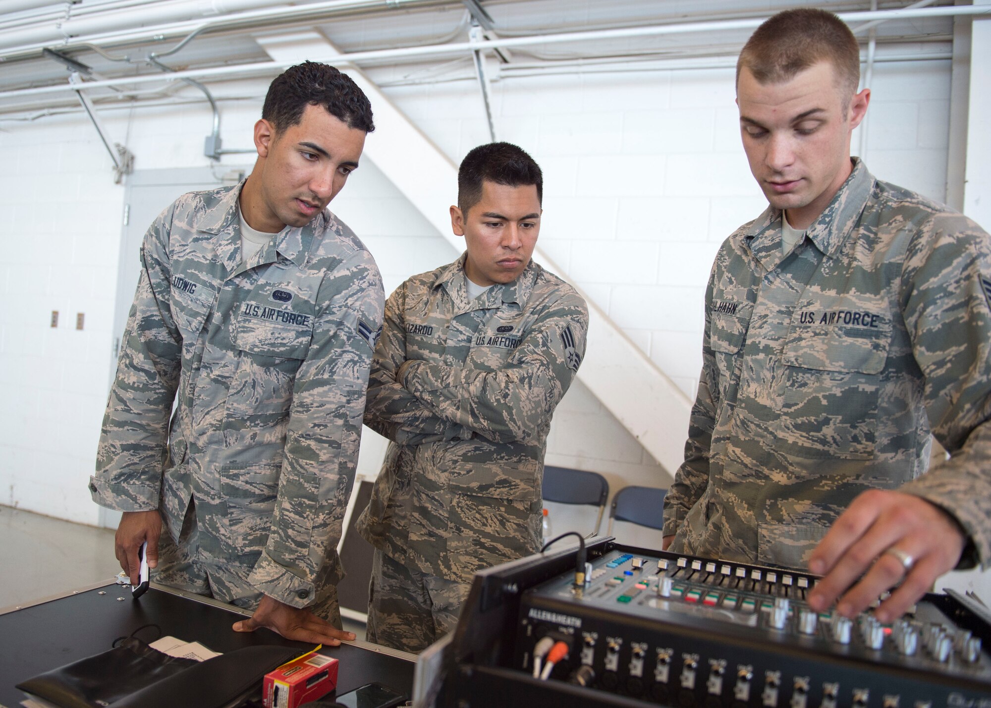 Airman 1st Class Sean Ludwig, left, Senior Airman Roy Lizardo, middle, and Staff Sgt. Andrew Muhlhahn, right, radio frequency systems technicians with the 1st Special Operations Communications Squadron, check a sound production mixer prior to a change of command ceremony at the Freedom Hangar on Hurlburt Field, Fla., July 15, 2016. Combined, these Airmen have provided audio production for more than 50 events in 2016. (U.S. Air Force photo by Senior Airman Krystal M. Garrett) 
