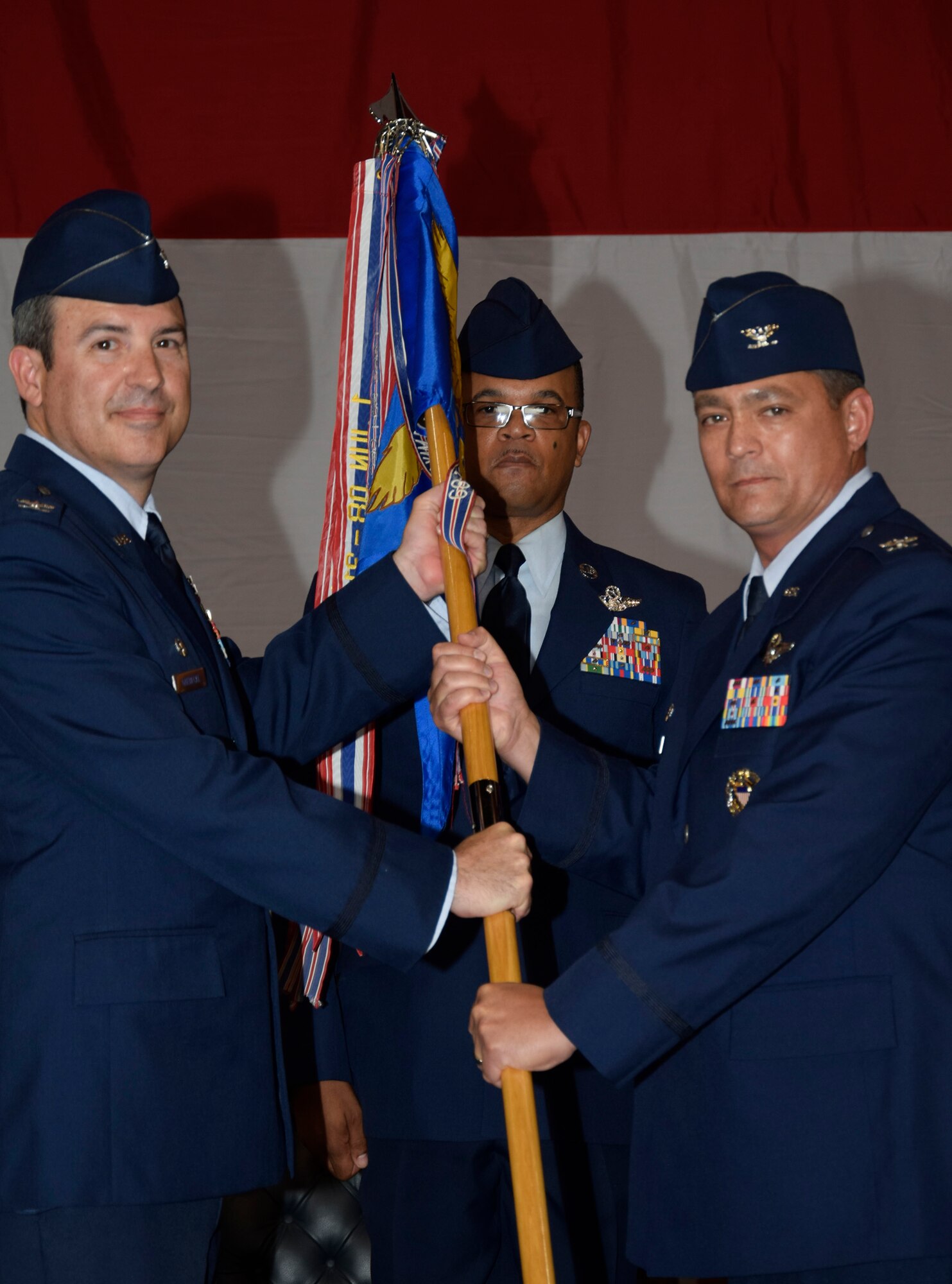 Col. Richard Land III accepts the 552nd Operations Group guidon from Col. David Gaedecke, 552nd Air Control Wing commander, during a change of command ceremony held July 8. Awaiting the guidon is Chief Master Sgt. Delano Barney, 552nd OG superintendent. (Air Force photo by Ron Mullan)