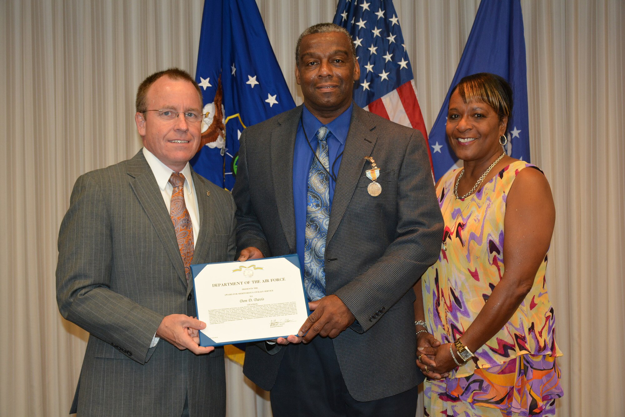 Jeffrey Allen, Air Force Sustainment Center executive director, left, presented Don Davis, AFSC Financial Management Directorate deputy director, with the Meritorious Civilian Service Medal prior to the June 7 AFSC staff meeting. Joining Mr. Davis for the presentation was his wife, Charlotte. (Air Force photo by Darren D. Heusel)