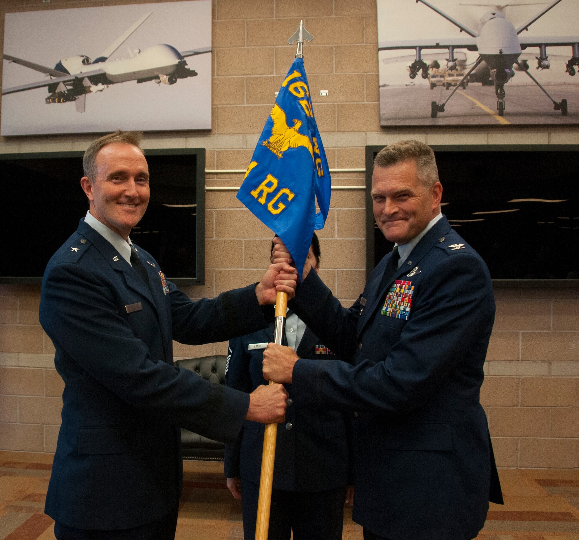 TUCSON, Ariz. -- Brig. Gen. Phil Purcell, commander of the 162nd Wing, left, passes the 214th Reconnaissance Group guideon to Col. James Thompson as a symbol of his assumption of command at Davis-Monthan Air Force Base July 9. Thompson's previously served as the vice commander of the 9th Air Expeditionary Task Force in Afghanistan. Now, as the top officer for the 214th Reconnaissance Group, he will lead a unit that provides highly sought intelligence, surveillance and reconnaissance capabilities to warfighters abroad 24 hours a day, every day. (Air National Guard photo by Staff Sgt. Gregory Ferreira)
