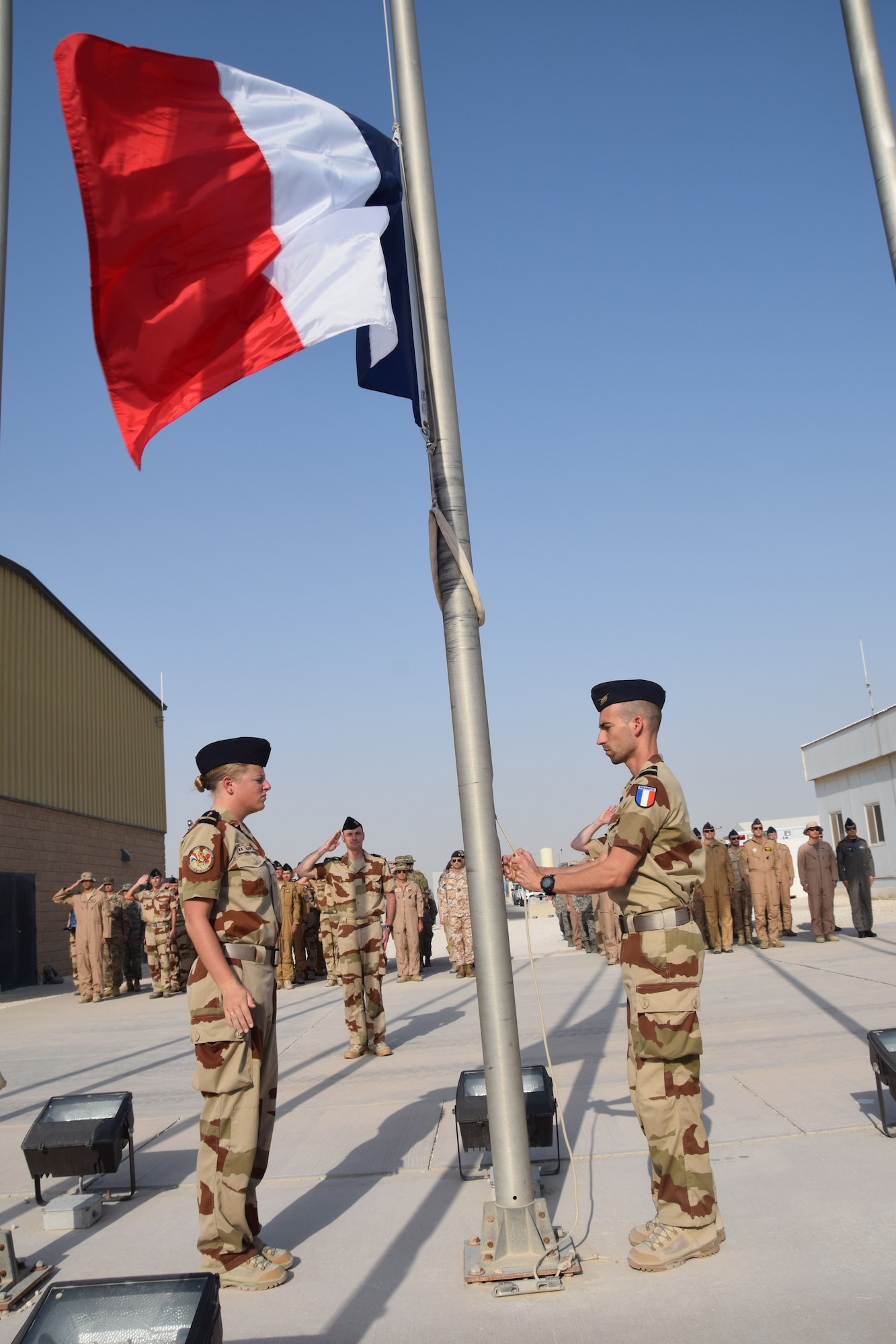 Members of the “garde d’honneur” from the French Air Force raise the French national flag, known as the Tricolour, to begin the Bastille Day ceremony July 14, 2016, at Al Udeid Air Base, Qatar, hours before the attack in Nice, France. France is one of 20 nations supporting the air Coalition that provides decisive air and space power to combat Daesh and other terrorist organizations and ensure the stability of the Southwest Asia region. (U.S. Air Force photo/ Carlos J. Treviño/Released)