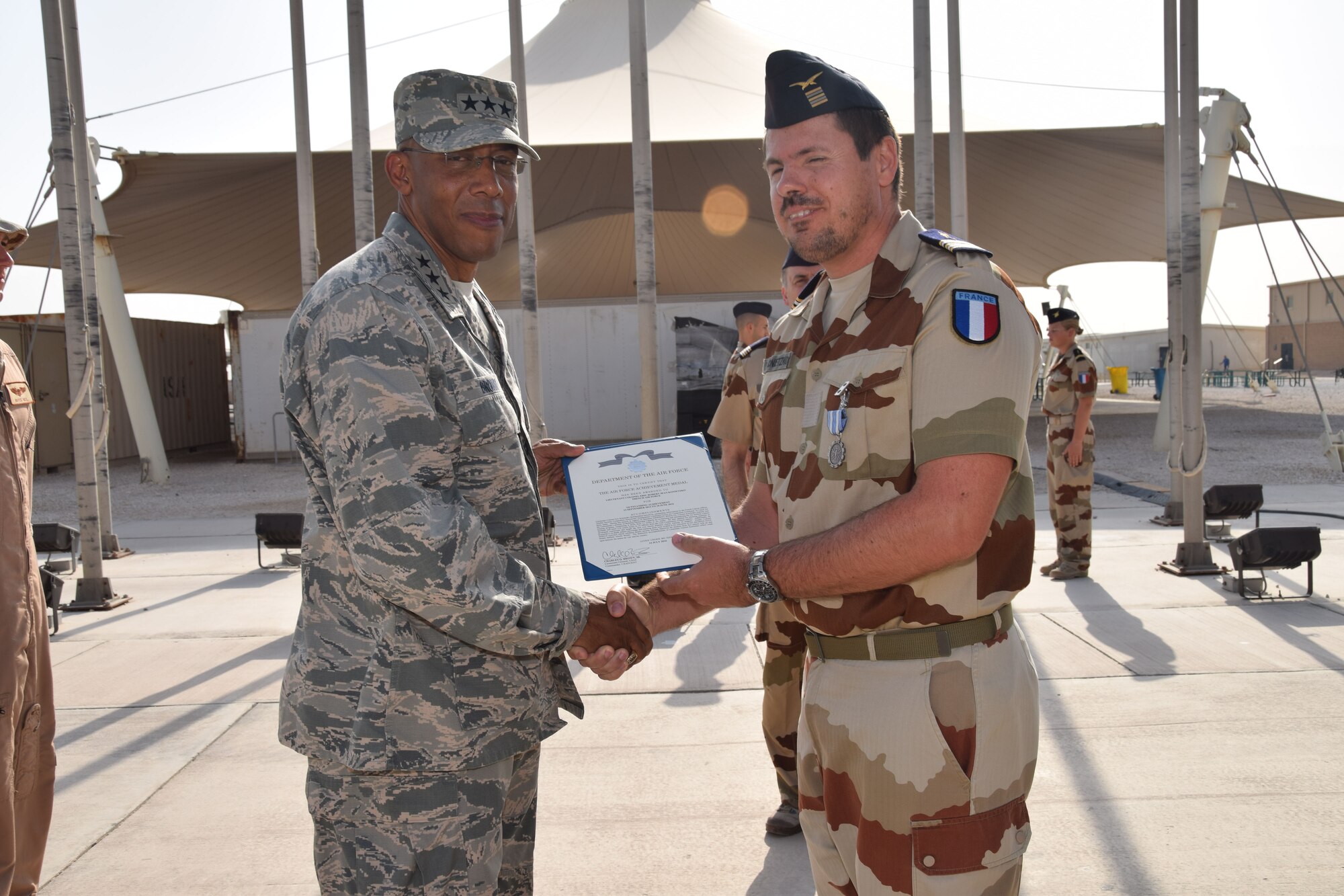Lt. Gen. Charles Brown, U.S. Air Forces Central Command commander, awards an Air Force Achievement Medal to French Air Force Lt. Col. Eric Konietzko, French liaison officer, during the Bastille Day ceremony July 14, 2016, at Al Udeid Air Base, Qatar. The Air Force Achievement Medal is given to members for outstanding achievement or meritorious service rendered specifically on behalf of the U.S. Air Force. France is one of 20 nations supporting the air Coalition that provides decisive air and space power to combat Daesh and other terrorist organizations and ensure the stability of the Southwest Asia region. (U.S. Air Force photo/Technical Sgt. Carlos J. Treviño/Released)
