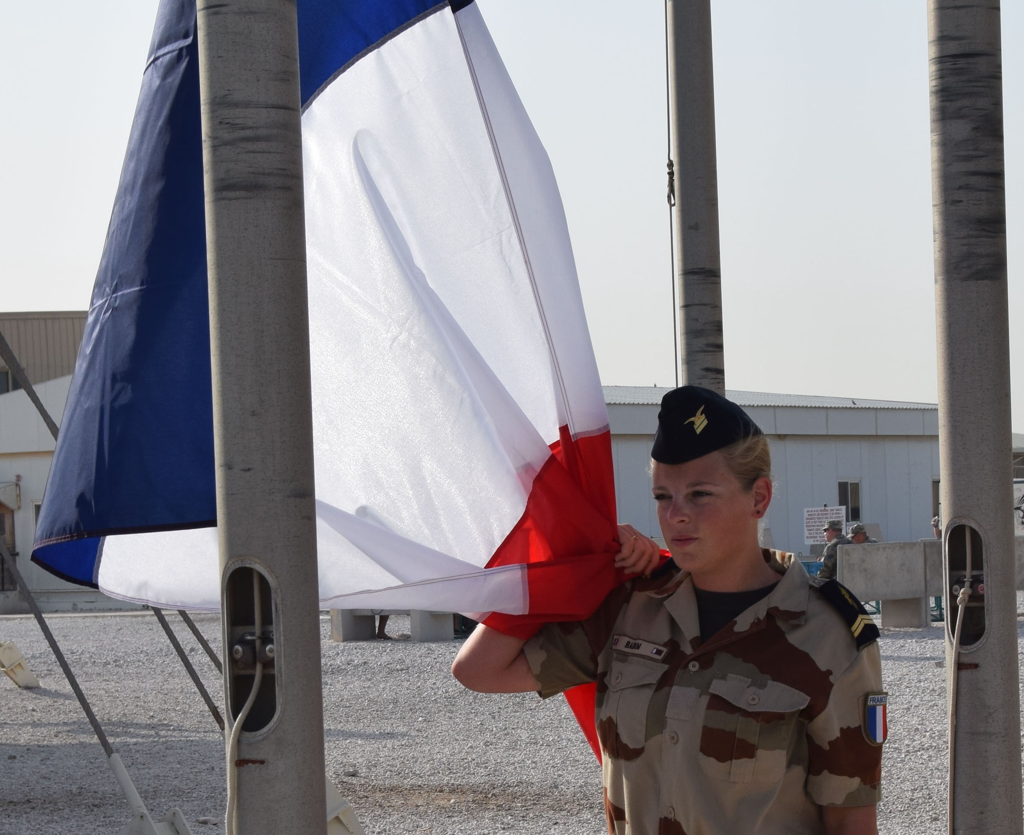 A member of the “garde d’honneur” from the French Air Force secures the French national flag, known as the Tricolour, before the Bastille Day ceremony July 14, 2016, at Al Udeid Air Base, Qatar. The French celebrate July 14 as Bastille Day to commemorate the storming of the royal jail called “la Bastille” in Paris at the beginning of the French Revolution in 1789. France is one of 20 nations supporting the air Coalition that provides decisive air and space power to combat Daesh and other terrorist organizations and ensure the stability of the Southwest Asia region. (U.S. Air Force photo/Carlos J. Treviño/Released))