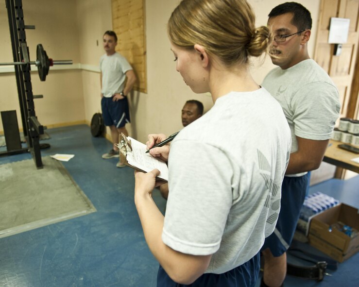 Master Sgt. Lindsey Glover, 455th Expeditionary Aircraft Maintenance Squadron, writes down the squat weight of a competitor, July 15, 2016, Bagram Airfield, Afghanistan. The 455th EAMXS held a power lifting competition that included squats, bench press, and deadlifts. (U.S. Air Force photo by Capt. Korey Fratini)