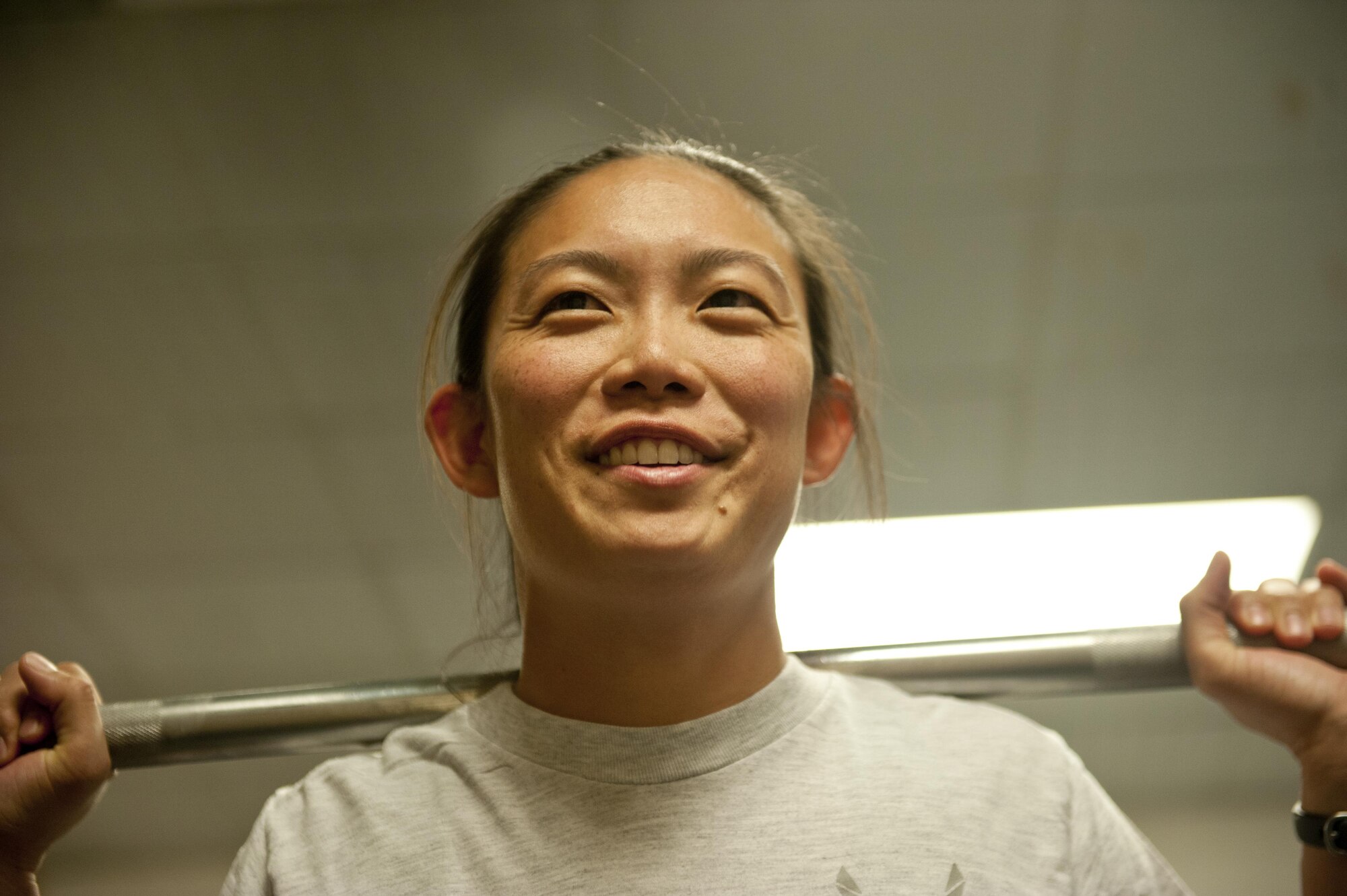 Capt. Kellianne Matsuoka, 455th Expeditionary Aircraft Maintenance Squadron, smiles after completing a squat during a power lifting competition, July 15, 2016, Bagram Airfield, Afghanistan. Airmen competed in three different power lifting events as part of a competition organized by the 455th EAMXS unit activities council.  (U.S. Air Force photo by Capt. Korey Fratini)