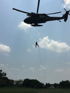Members of the 1st Battalion, 228th Aviation Regiment from Joint Task Force-Bravo and Special Operations Command South conduct Fast Rope Insertion and Extraction System training from a UH-60 Black Hawk helicopter with Salvadorian military May 24 in El Salvador. JTF-Bravo and other U.S. Military elements, under the auspices of U.S. Southern Command, routinely conduct combined training and exercises with Partner Nation security forces in multiple Central American nations, improving the safety and security in the CENTAM region and southern approaches to the United States. According USSOUTHCOM officials, Salvadorian forces exemplify the command’s security cooperation objectives to enhance the capability of partners to operate successfully in contingency, peacekeeping, humanitarian, disaster and stability operations. (Courtesy Photo)