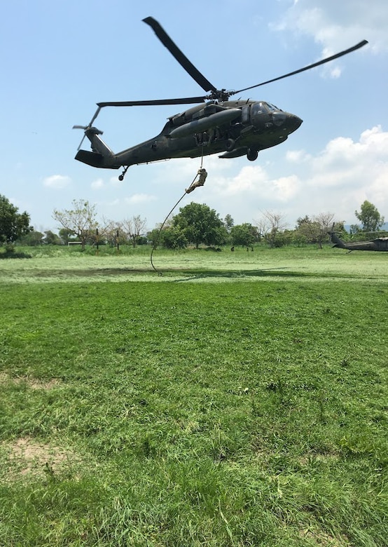 Members of the 1st Battalion, 228th Aviation Regiment from Joint Task Force-Bravo and Special Operations Command South conduct Fast Rope Insertion and Extraction System training from a UH-60 Black Hawk helicopter with Salvadorian military May 24 in El Salvador. Salvadorian military members received incremental training that began with helicopter familiarization and progressed to rappelling from, and being hoisted into, the 1-228th AVN’s Black Hawks flying at heights of up to 90 feet. This training is crucial to both U.S. and Salvadorian military members’ ability to safely conduct aerial operations for a variety of missions that include search and rescue, humanitarian aid and disaster relief, troop movements, counter-transnational organized crime operations and even firefighting efforts. (Courtesy Photo)