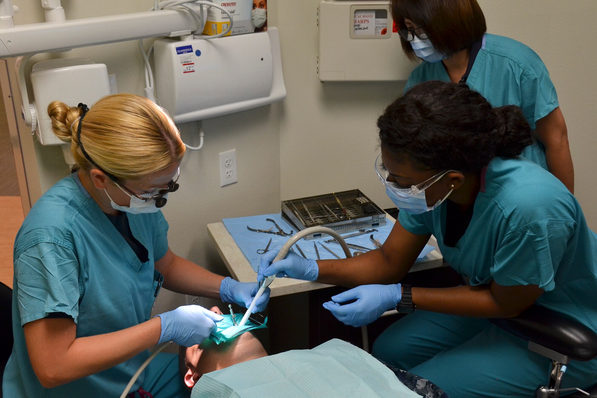 Airman 1st Class Franchestar Witherspoon (right), dental technician, 117th Medical Group assists Lt. Cmdr. Sara Chilcutt, fleet liason officer, Naval Branch Health Clinic, Naval Station San Diego in providing a dental procedure to a patient in the clinic, in San Diego, Calif., June 23, 2016.  The 117 MDG trained with the U.S. Navy at Naval Medical Center San Diego.  The training included Airmen being implemented in real world U.S. Naval operations.  (U.S. Air National Guard photo by Staff Sgt. Jeremy Farson/Released)   