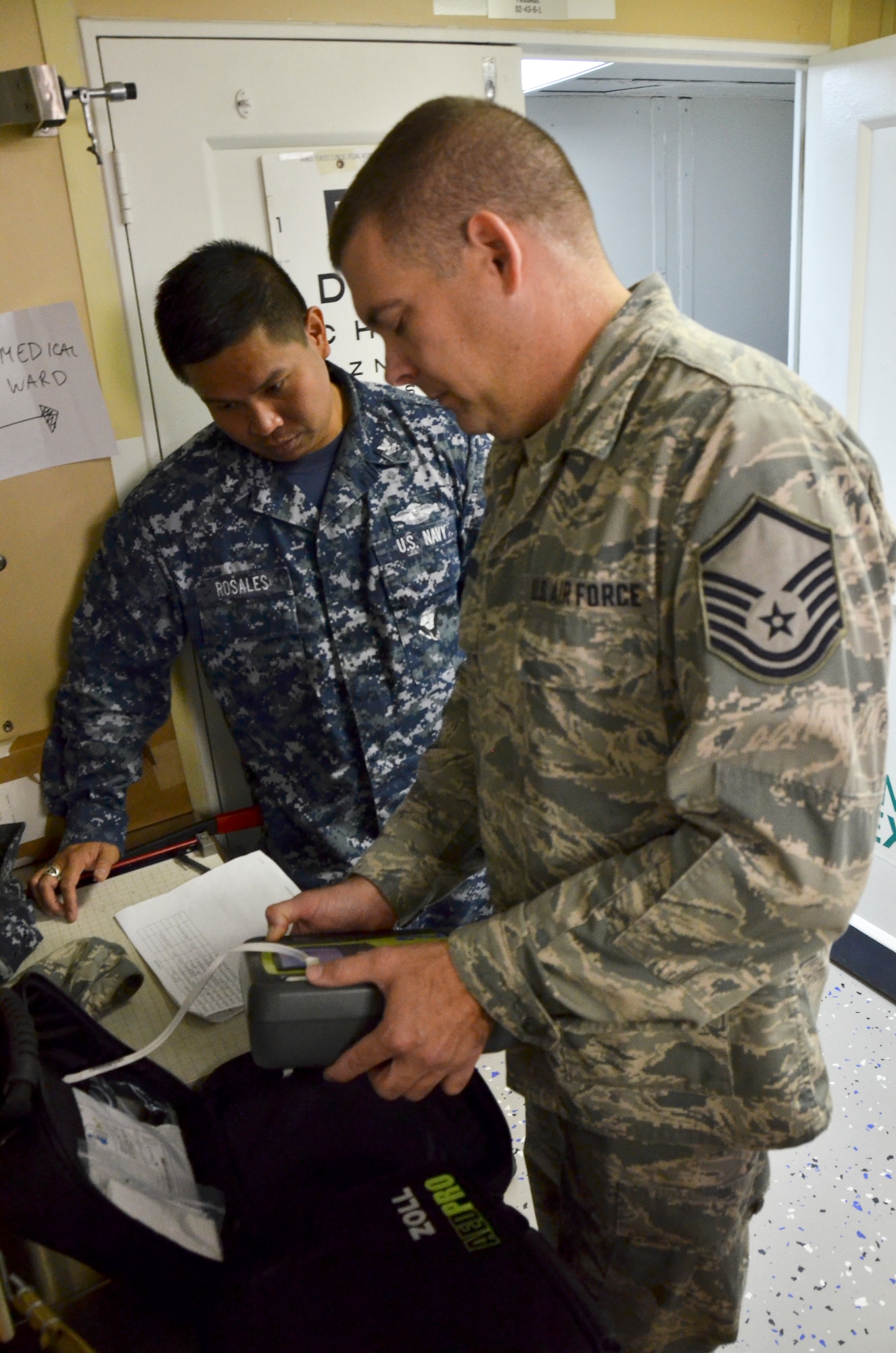 Master Sgt. Raymond Jansen (near), biomedical equipment technician, 117th Medical Group and Petty Officer 2nd Class Victoriano Rosales, biomedical equipment technician, 32nd Ships and Clinics, troubleshoot medical equipment on board a naval vessel in San Diego, Calif., June 22, 2016.  The 117 MDG trained with the U.S. Navy at Naval Medical Center San Diego.  The training included Airmen being implemented in real world U.S. Naval operations.  (U.S. Air National Guard photo by Staff Sgt. Jeremy Farson/Released)   