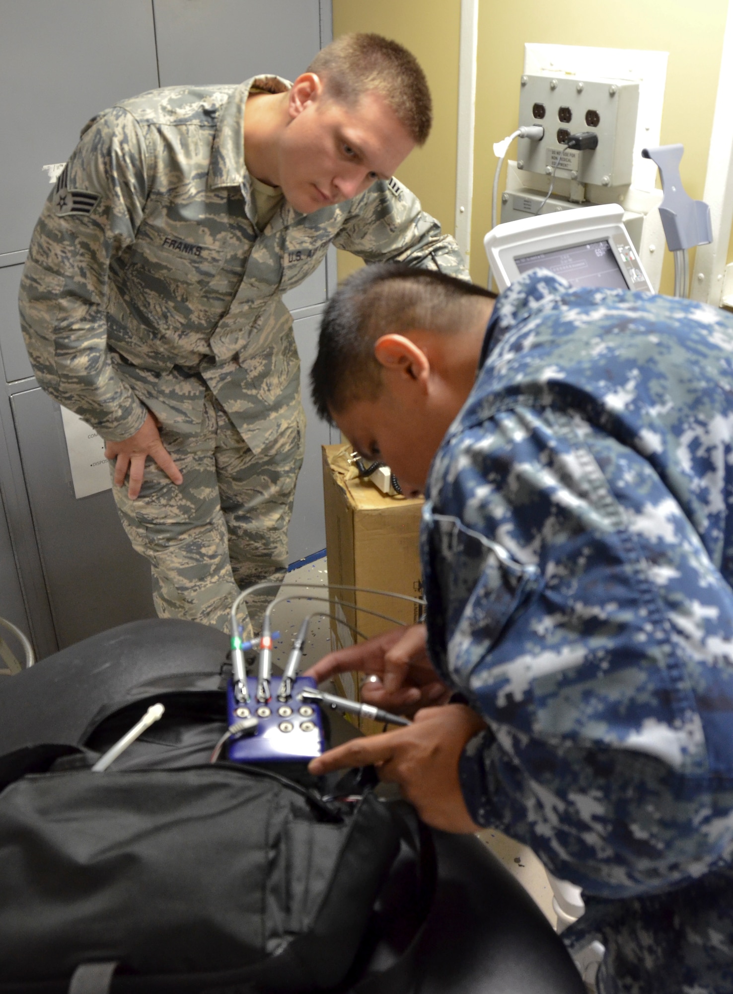 Senior Airman Jaron Franks (left), biomedical equipment technician, 117th Medical Group and Petty Officer 2nd Class Victoriano Rosales, biomedical equipment technician, 32nd Ships and Clinics, troubleshoot medical equipment on board a naval vessel in San Diego, Calif., June 22, 2016.  The 117 MDG trained with the U.S. Navy at Naval Medical Center San Diego.  The training included Airmen being implemented in real world U.S. Naval operations. (U.S. Air National Guard photo by Staff Sgt. Jeremy Farson/Released)   