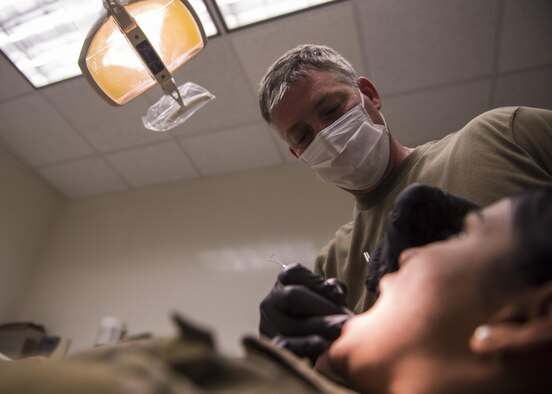 U.S. Army Capt John Mann, 129th Area Support Medical Company dentist, examines a patient’s teeth, Bagram Airfield, Afghanistan, July 16, 2016. The Dental Clinic at Joint-Craig Theater hospital sees an average of 100 patients a month and performs emergency dental procedures to include root canals and extractions. (U.S. Air Force photo by Senior Airman Justyn M. Freeman)