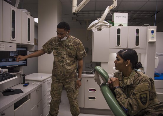 U.S. Army Specialist Anfernee Grant, 129th Area Support Medical Company dental technician, shows a patient X-rays of her teeth, Bagram Airfield, Afghanistan, July 16, 2016. Exams are conducted to detect signs of decay or broken teeth. (U.S. Air Force photo by Senior Airman Justyn M. Freeman)