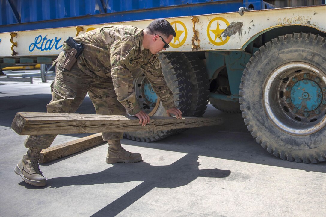 Senior Airman Brandon Misita puts a beam in front of a truck tire during a high-mobility multipurpose wheeled vehicle delivery at Bagram Airfield, Afghanistan, July 14, 2016. Misita is a material recovery specialist assigned to the 455th Expeditionary Logistics Readiness Squadron Central Command. Misita places beams in front of the tires so the truck stays stable as the team unloads the cargo. Air Force photo by Senior Airman Justyn M. Freeman