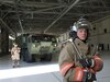 US Army firefighter standing inside, HEMTT and fellow firefighter in background.