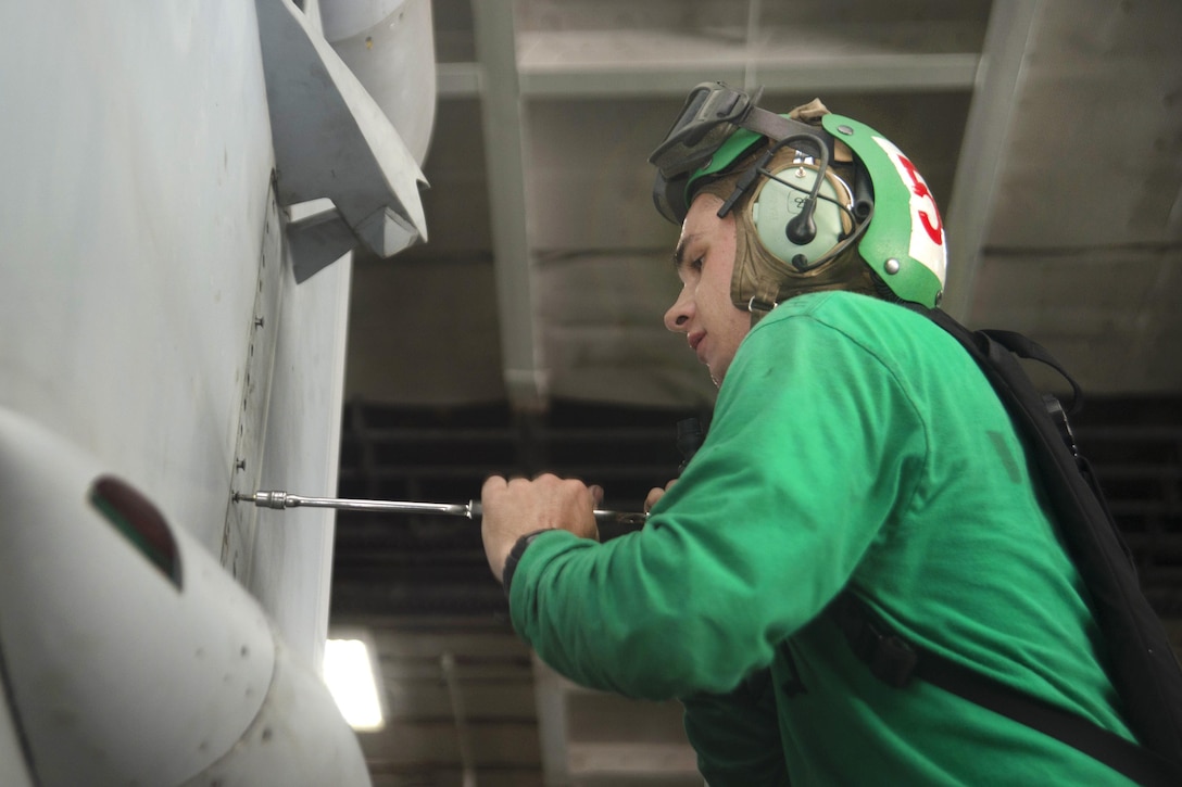 Navy Seaman James Rumbaugh assigned to the Zappers Electronic Attack Squadron 130 replaces panels on an EA-18G Growler in the hangar bay of the aircraft carrier USS Dwight D. Eisenhower in the Gulf of Aden, July 15, 2016. Rumbaugh is an aviation electronics technician airman. Navy photo by Seaman Dartez C. Williams