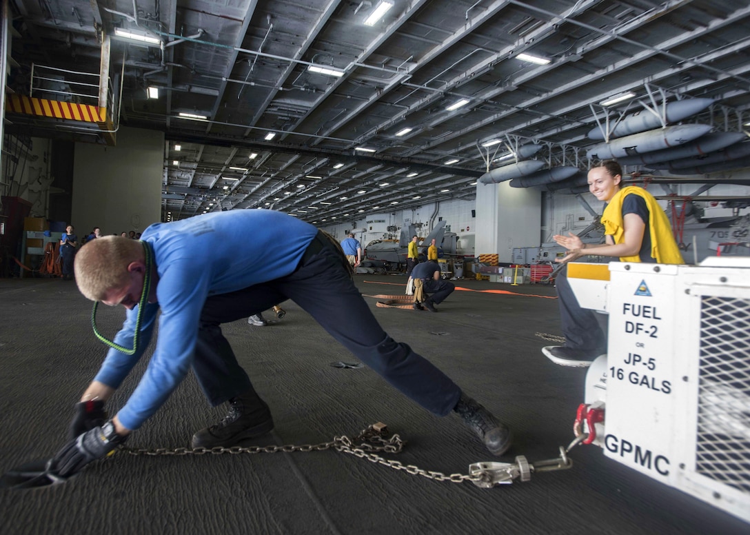 Navy Seaman Isaiah Winburn secures a spotting dolly during a competitive relay in the hangar bay of the aircraft carrier USS Dwight D. Eisenhower in the Gulf of Aden, July 15, 2016. Winburn is an aviation boatswain's mate handling airman apprentice. Navy photo by Seaman Apprentice Joshua Murray