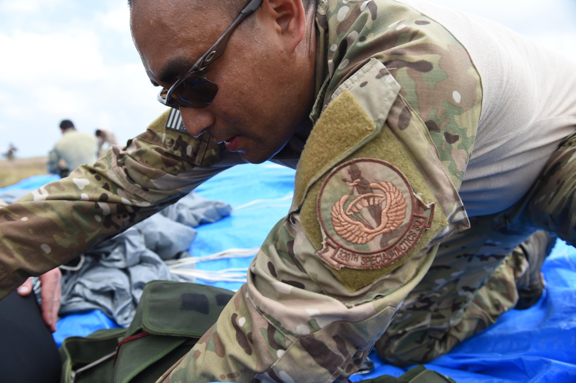 A parachute rigger with the 320th Special Tactics Squadron re-packs a parachute after a multi-aircraft, joint airborne operation with special operations assets and conventional forces from all four branches of the U.S. Armed Forces as part of Rim of the Pacific (RIMPAC) 2016 to strengthen their relationships and interoperability with their partners, Pohakuloa Training Area, Hawaii, July 14, 2016. The world's largest international maritime exercise, RIMPAC provides a unique training opportunity that helps participants foster and sustain the cooperative relationships that are critical to ensuring the safety of sea lanes and security on the world's oceans. (U.S. Air Force photo by 2nd Lt. Jaclyn Pienkowski/Released)